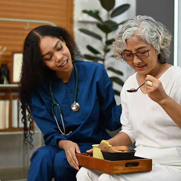 nurse helping senior woman with her food